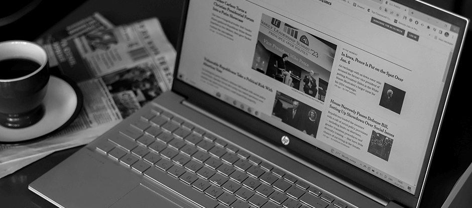 News website displayed on laptop with a cup of coffee next to it