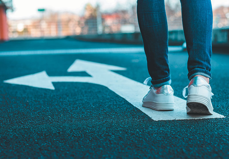 A person walking with direction arrow on road